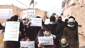 سوريات مع أطفالهن يرفعن لافتات مناهضة لنظام بشار الأسد خلال مظاهرة احتجاجية في داريا قرب دمشق (رويترز)