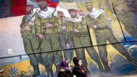 امرأتان في طهران تمرّان قرب لوحة كبيرة تعكس جنوداً إيرانيين أثناء الحرب مع العراق (أ ف ب)