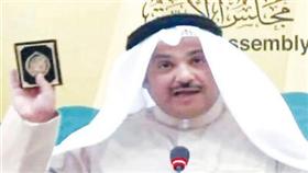 - محمد الجويهل رافعاً القرآن الكريم خلال مؤتمره الصحافي