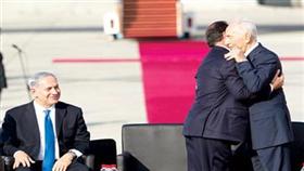 الرئيسان الفرنسي فرانسوا أولاند والإسرائيلي شيمون بيريز يتعانقان فيما يبتسم نتنياهو في مطار بن غوريون أمس