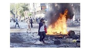 امرأة وطفلها يسيران وسط اشتباكات بين المحتجين الأكراد والشرطة التركية في ديار بكر (أ.ف.ب)