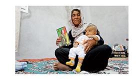 سيدة كردية تحمل صورة لابنتها المقاتلة التي قتلت في كوباني (رويترز)
