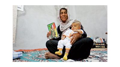 سيدة كردية تحمل صورة لابنتها المقاتلة التي قتلت في كوباني (رويترز)