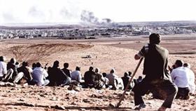 عدد من الأكراد يراقبون القصف الجوي على مدينة كوباني من أعلى تلّة من الجهة التركية (أ ف ب)