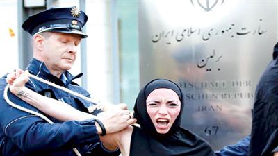 شرطي ألماني يعتقل ناشطة خلال احتجاج أمام سفارة إيران في برلين على إعدام فتاة إيرانية قبل أيام (رويترز)