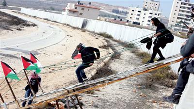 نشطاء فلسطينيون يخترقون الجدار الإسرائيلي العازل للوصول إلى القدس (أ. ف. ب)