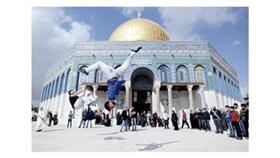 شبان فلسطينيون يؤدون حركات الباركور خارج قبة مسجد الصخرة المشرفة بعد صلاة الجمعة في القدس (أ ف ب)
