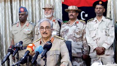 الجنرال خليفة حفتر يتحدث لعدد من وسائل الإعلام خلال مؤتمر صحافي في بنغازي ويبدو خلفه عدد من القادة العسكريين الموالين له (رويترز)