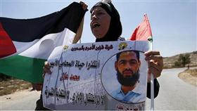 فلسطينية تحمل لافته عليها صورة الأسير محمد علان وعلم فلسطين