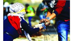 شابة فلسطينية مُلثمة تمد زميلها بالحجارة خلال اشتباكات مع قوات الاحتلال
