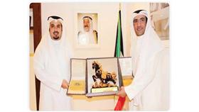 الشيخ خالد الأحمد يتسلم درع التكريم من د.فهد الهاجري