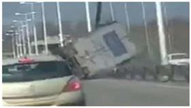 بالفيديو - انقلاب شاحنة على جسر مرتفع بفعل الرياح
