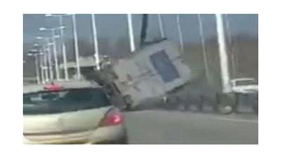 بالفيديو - انقلاب شاحنة على جسر مرتفع بفعل الرياح